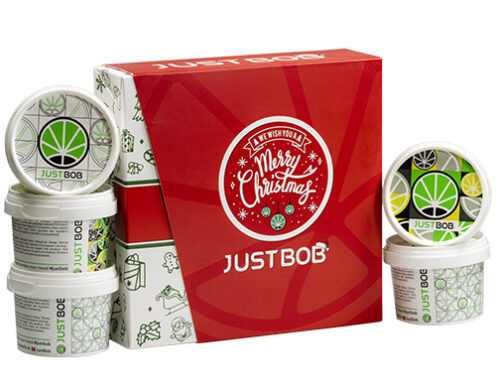Scatola Justbob XMAS KIT aperta con diversi contenitori di cannabis light con marchio natalizio e design a foglia di cannabis, perfetta per i regali festivi
