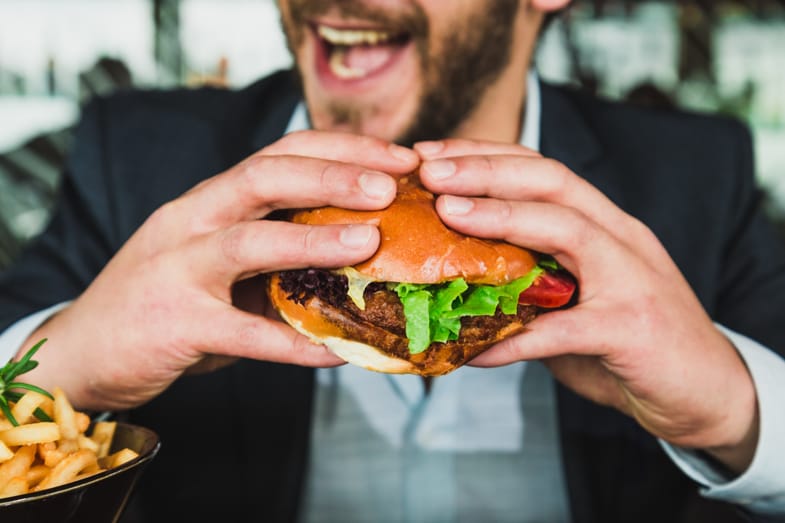 Uomo che mangia un hamburger | Justbob