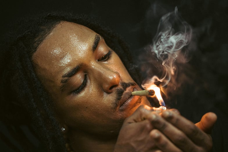 Uomo afroamericano che fuma una sigaretta con cannabis | Justbob